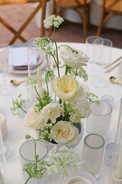 Bir olay için güzel dekore edilmiş bir masada beyaz güllerin dikey çekimi.