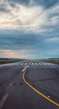 Kasvetli bir gökyüzünün altında boş bir asfalt otoyolun dikey görüntüsü.