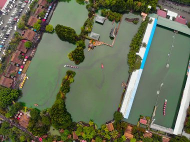 Yeşil ağaçlarla çevrili göletlerin ve park yerinin yakınındaki evlerin havadan görünüşü.