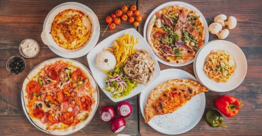 Prosciutto, yeşillik, patates kızartması ve lezzetli makarnadan oluşan farklı pizzalar.