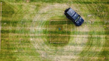 Yeşil bir arazide donut yapan siyah bir off-road arabasının üst görüntüsü.