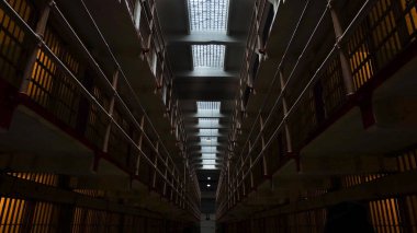 Hücreleri ve balkonları olan bir hapishane koridoru.