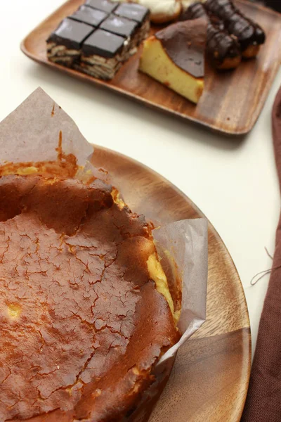 一个美味的圣塞巴斯蒂安芝士蛋糕垂直拍摄和不同的糕点放在桌上的托盘上 — 图库照片