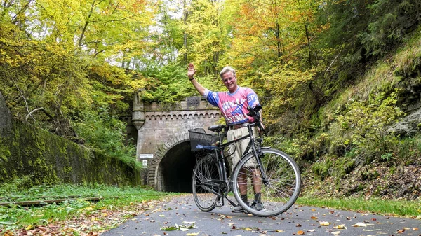 クルシュテッタートンネルのある自転車道を走っている白人の老人とドイツの秋の木 — ストック写真