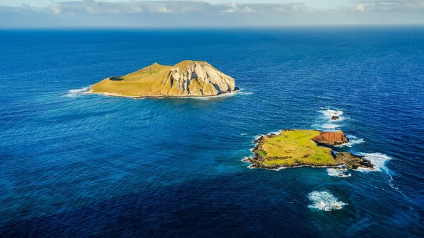 An aerial shot of two small islands surrounded by a deep blue ocean in the daytime