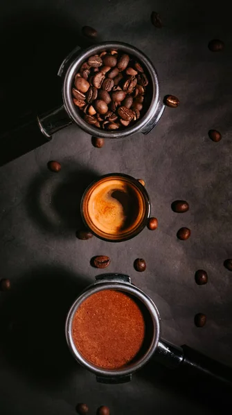 A vertical closeup of the cup of Espresso with coffee beans on the dark background. Top view.