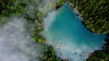 Adada yeşil ağaçlarla çevrili güzel bir turkuaz su üzerinde insansız hava aracı.