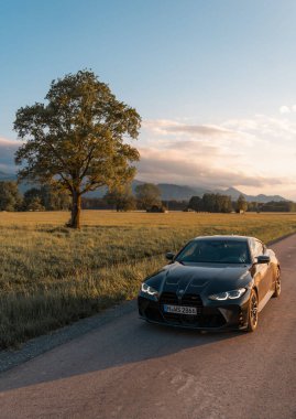 Günbatımında modern bir BMW M4 'ün, Dağ v. lüks spor arabalı görüntüsü birçok sürücünün hayalindeki arabadır.