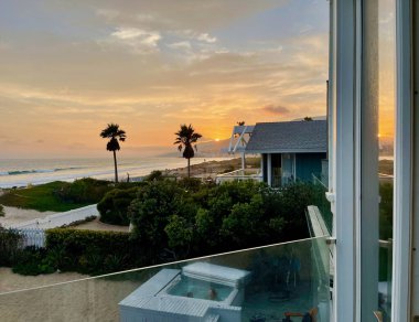 Gün batımında etrafı binalarla çevrili Malibu sahilinin güzel bir manzarası.