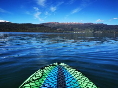 Dağların önünde yeşil ile kaplanmış denizde yüzen bir teknenin güzel bir görüntüsü.