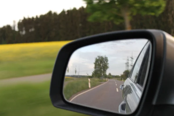 자동차의 거울을 클로즈업 모습은 초목으로 둘러싸인 도로를 반영한다 — 스톡 사진