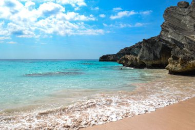 Deniz üzerindeki bulutlu mavi gökyüzü yazın kumlu sahilden yakalanır.