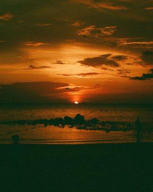 Gün batımında denizdeki devasa taşlardan oluşan dikey bir görüntü..