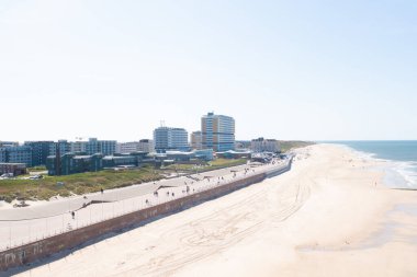 Güneşli bir günde arka planda modern mimari olan bir kumsal manzarası.