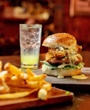 Lezzetli bir burgerin dikey pozu patates kızartması ve bir içki.
