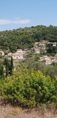 Ağaçlarla çevrili, bulutsuz arka planda binaların dikey görüntüsü.
