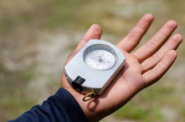 Elinde pusula tutan bir erkek, ormanda yön arıyor.