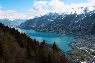 İsviçre 'deki dağların büyüleyici manzarası. Mavi bir gölü ve dipte bir kasabası var.