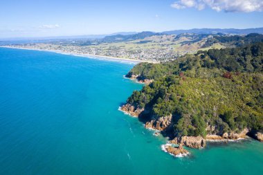 Yeni Zelanda 'da mavi gökyüzünün altında suyla çevrili bir dağ manzarası.