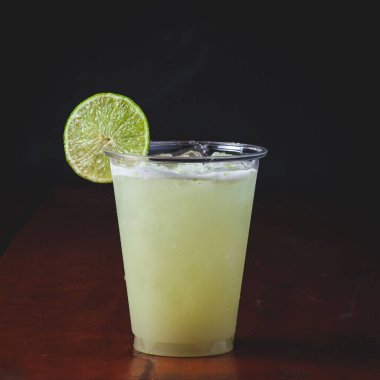 Plastik bardakta limon dilimli bir kokteylin yakın çekimi.