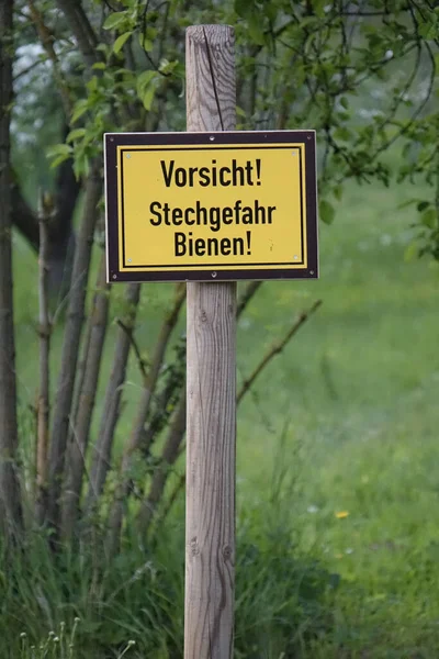 Black and yellow warning sign \'Attention! Danger of stings. Bees!\' in spring (horizontal), Hildesheim, Lower Saxony, Germany