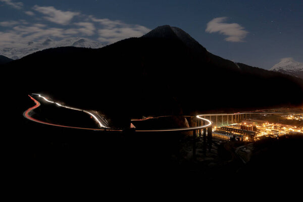 A distant view of the long exposure roads surrounded by mountains in the dark