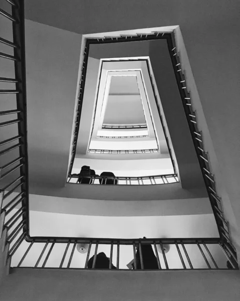 一幢公寓楼里有黑色扶手和白色墙壁的螺旋形楼梯的灰度照片 — 图库照片