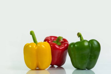 Beyaz arka planda kırmızı, yeşil ve sarı biberler, kopyalama alanı, konsept: sağlıklı çiğ gıda