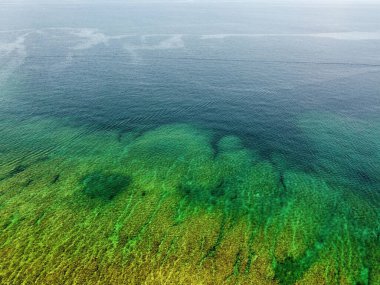 Deniz manzarasının berrak, durgun suyunun yeşilden maviye dönüşünün hava görüntüsü.