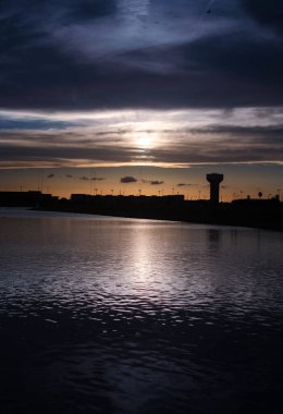Huzurlu denizin üzerinde bir duvarla çevrili karanlık günbatımının manzaralı bir görüntüsü.