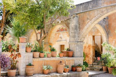Yunanistan 'daki Agia Triada Manastırı' nda paslı duvarların etrafında seramik kaplarla aydınlık bir yaz günü.