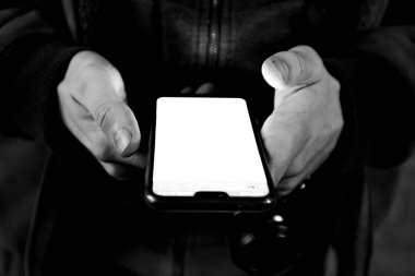 Elinde telefon olan birinin gri tonlu görüntüsü.