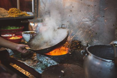 Malezya sokak restoranında uçan kıvılcımlarla kızartma tavasına yakın çekim.