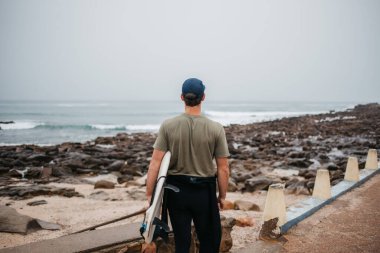 Deniz kıyısında yürüyen genç bir erkek.