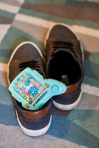カーペットの床に靴の中に水とプラスチック製のゲーム機 — ストック写真