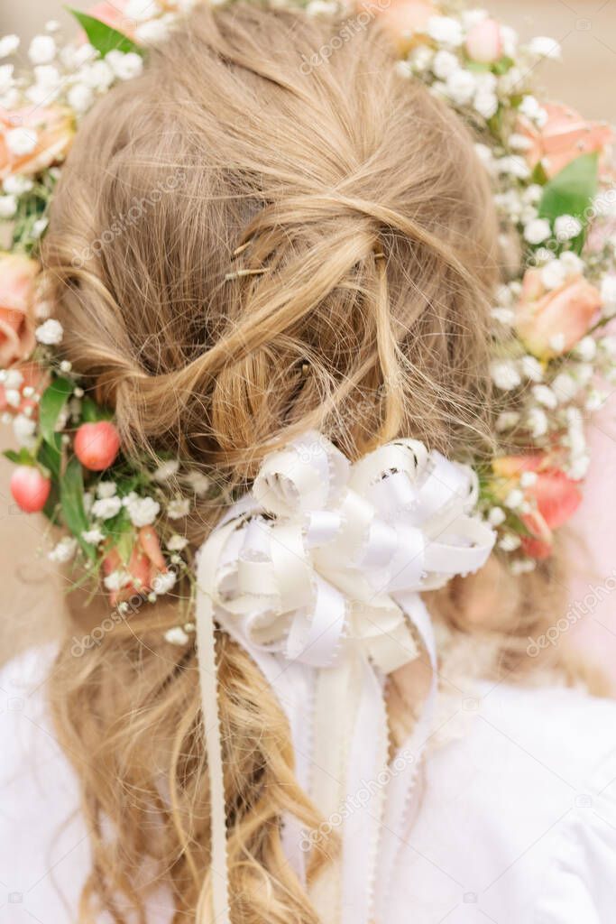 A beautiful bridal hairstyle with a flower crown and white bow