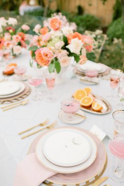 Zarif sofra takımı ve çiçek süslemeleri olan bir açık hava düğün masasının dikey görüntüsü.