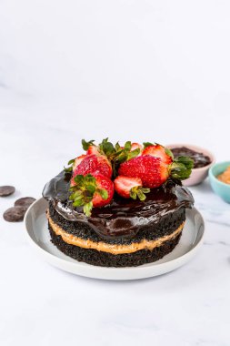 Çilekle süslenmiş çikolatalı pastanın dikey görüntüsü.