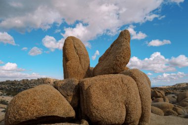 Çölde güneşli bir günde mavi bulutlu bir gökyüzüne karşı kırmızı kayalar.