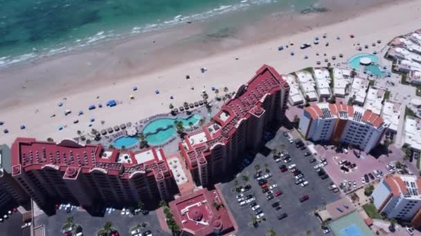 在阳光明媚的一天 拍了一张海滨酒店的无人驾驶照片 里面有游泳池 还建在沙滩上 — 图库视频影像