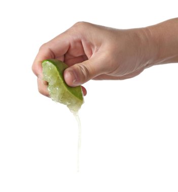 Beyaz bir arka planda yeşil bir limonu sıkan bir erkek el.