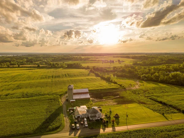 A bird\'s eye view of a factory in green fields at sunset near Owasco Lake in Auburn, New York