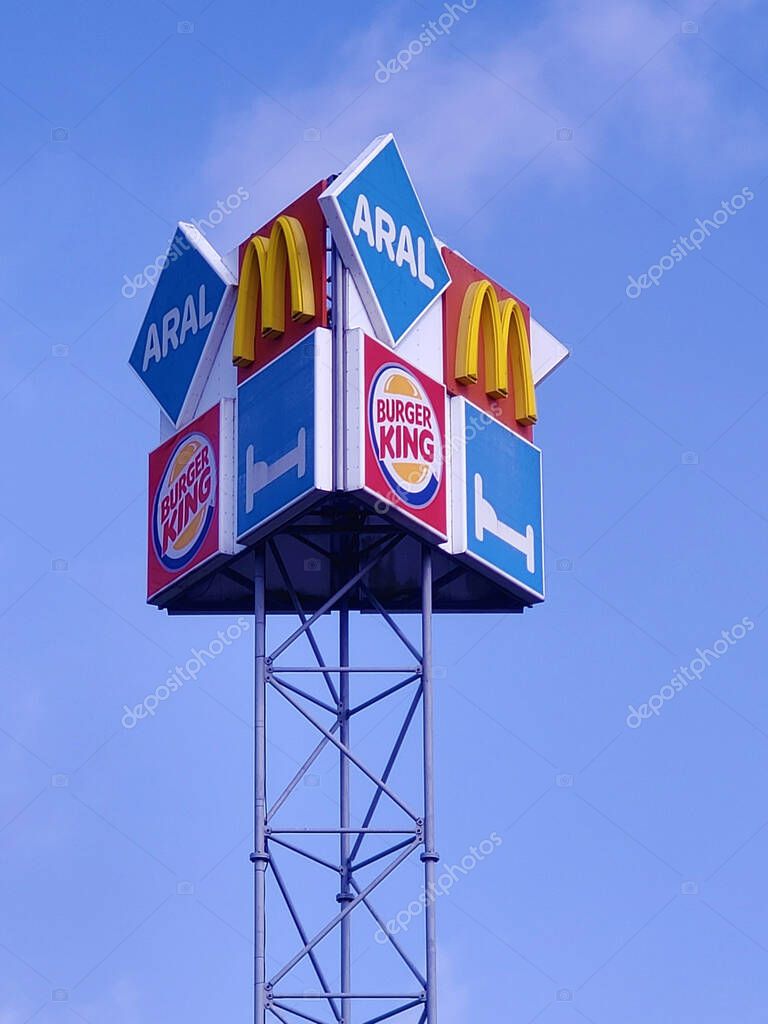 14 April 2022, Ladbergen, NRW, Germany, Advertising signs for ARAL gas stations, McDonalds and Burger King fast food and a motel (vertical)