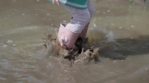 一个穿着粉色靴子的小女孩跳进池塘里的特写镜头 — 图库视频影像