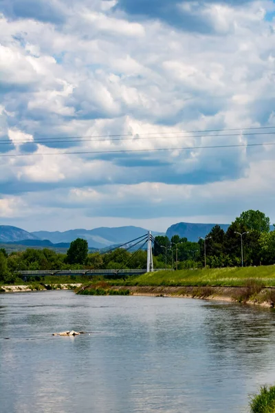 Arka Planda Asma Köprü Olan Bulutlu Bir Gökyüzünün Altındaki Nehir — Stok fotoğraf
