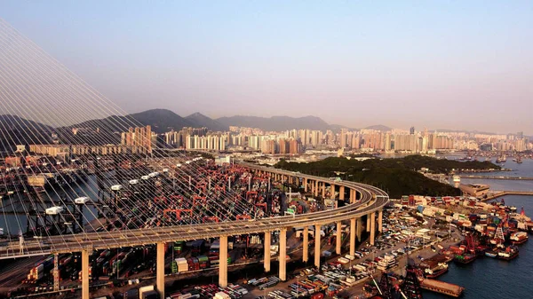 A bird\'s eye view of the Stonecutter Bridge against the cityscape of Hong Kong at sunset