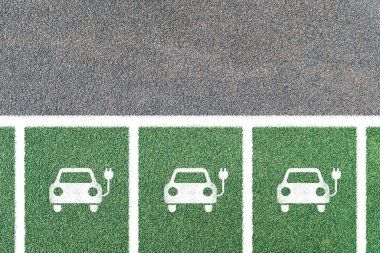 Birden fazla elektrikli araba sadece sembollerle park edilmiş. Elektrikli araç şarj istasyonu ve elektrik prizi ikonu. Boşluğu kopyala
