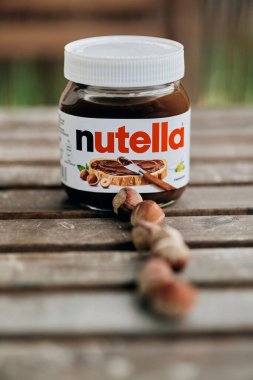 Tahta masaya serilmiş bir kavanoz Fererro Nutella fındığı.