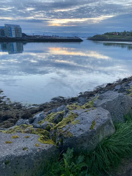 アイスランドのレイキャヴィクの岩の多い湖の上に沈む夕日の空の垂直ショット — ストック写真