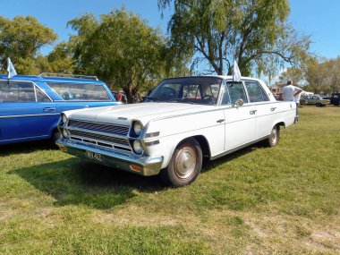 Eski beyaz AMC Rambler Büyükelçisi 990 sedan 1965 kırsal kesimde. Doğa, çimen, ağaçlar. Klasik araba şovu. Kopyalama alanı